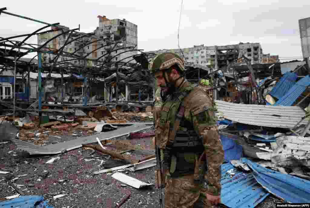 Un soldat ucrainean se plimbă pe lângă clădirile rezidențiale din Bahmut avariate de bombardamente.