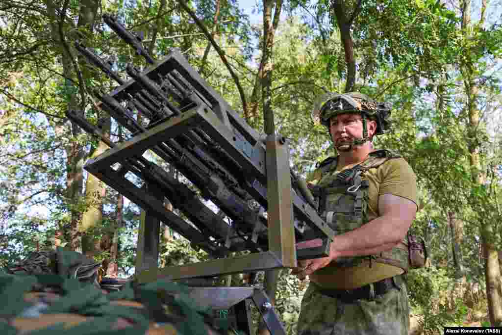 Un soldat rus cu o mitralieră anti-dronă improvizată, aparent formată din cinci puști automate AK-74 prevăzute cu tije care permit tragerea simultană din toate armele.