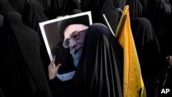 Илустрација - Жена со фотографија од ајатолахот Хамнеи на собир