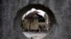O casă puternic distrusă de bombardamentele rusești este văzută prin gard de beton, Kiev, Ucraina, 14 decembrie 2022