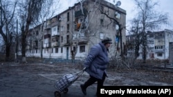 O localnică se îndreaptă spre punctul de distribuire a ajutoarelor umanitare în fața unor locuințe care au fost avariate de bombardamentele rusești în Kupyansk, în regiunea ucraineană Harkov, la 28 decembrie.