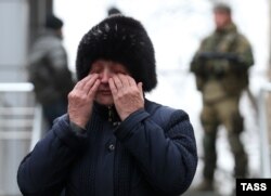 Родственница одного из шахтеров. На заднем плане – вооруженные сепаратисты так называемой "ДНР"