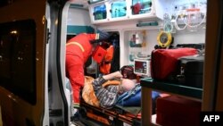 Salvatorii ucraineni acordă ajutor unui bărbat rănit în urma unui atac cu dronă asupra unei zone rezidențiale din Harkov, în seara zilei de 2 mai.