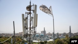 Un steag taliban flutură lângă echipamentele de telecomunicații instalate pe acoperișul unei clădiri care oferă servicii de internet în provincia Balkh. 16 septembrie 2025.