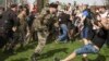 Человек в камуфляжной форме и папахе бьет участника акции "Он нам не царь" на Пушкинской площади в Москве, 5 мая 2018 года