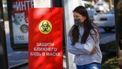 Девушка проходит мимо надписи, предупреждающей об опасности коронавируса.