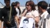 Наталья Эстемирова держит плакат "Верните Булата" на акции в поддержку сотрудника "Мемориала", пропавшего без вести в Чечне в 2007 году 