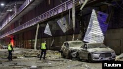 Polițiști ucraineni, inspectând un centru comercial avariat în timpul unui atac rusesc cu drone asupra Kievului, pe 4 mai 2025 