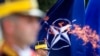 Un soldat român din garda de onoare, susținut de drapelul NATO, stă nemișcat în timpul ceremoniei de depunere a coroanei, așa cum se vede prin flacăra eternă, la Memorialul Soldatului Necunoscut, cu ocazia comemorării Zilei Eroilor, la București, România, 28 mai 2020.