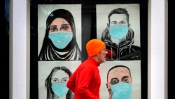 Бегущий мужчина на фоне плакатов с изображениями людей в масках. Льюистон (Мэн), 16 ноября 2020 года.