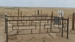 Коронавирустан қайтыс болған кісіні жерлеу кезінде қабір басында құран оқып тұрған молда мен марқұмды жерлеуге келген арнайы киімдегі адамдар. Алматы облысы, Қараой ауылы маңы. 16 маусым 2020 жыл.