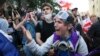Un protestatar se ceartă cu ofițerii de poliție în timpul unui protest al opoziției împotriva legii „agentului străin” în fața clădirii parlamentului din Tbilisi, pe 28 mai.