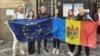Cetățeni moldoveni din România țin steaguri europene și moldovenești la o secție de votare pentru diaspora din București, 28 septembrie 2025.