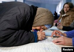 O bătrână semnează înainte de a primi buletinul de vot în Sloviansk, 26 octombrie, 2014