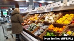 Дүкендегі көкөніс өнімдері сөресінің алдында тұрған тұтынушы. (Көрнекі сурет.)
