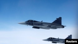 Imagine generică - Avioane de vânătoare Saab JAS 39 Gripen ale Forțelor Aeriene Suedeze zboară alături de o aeronavă care simulează interceptări aeriene 