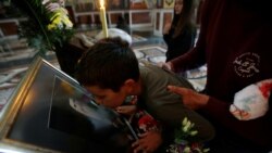 Ребенок в черногорской церкви прикасается губами к изображению умершего митрополита Амфилохия.