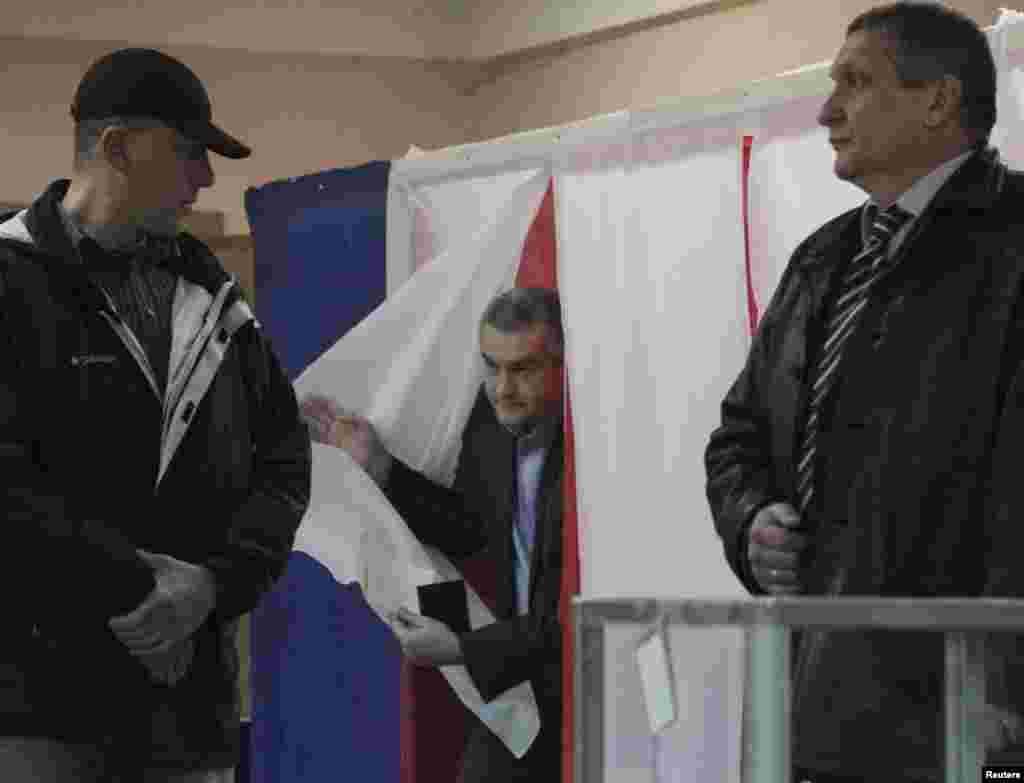 Прэм&#39;ер-міністар Крыму Сяргей Асёнаў (у цэнтры) выходзіць з кабінкі для галасаваньня ў Сімфэропалі.